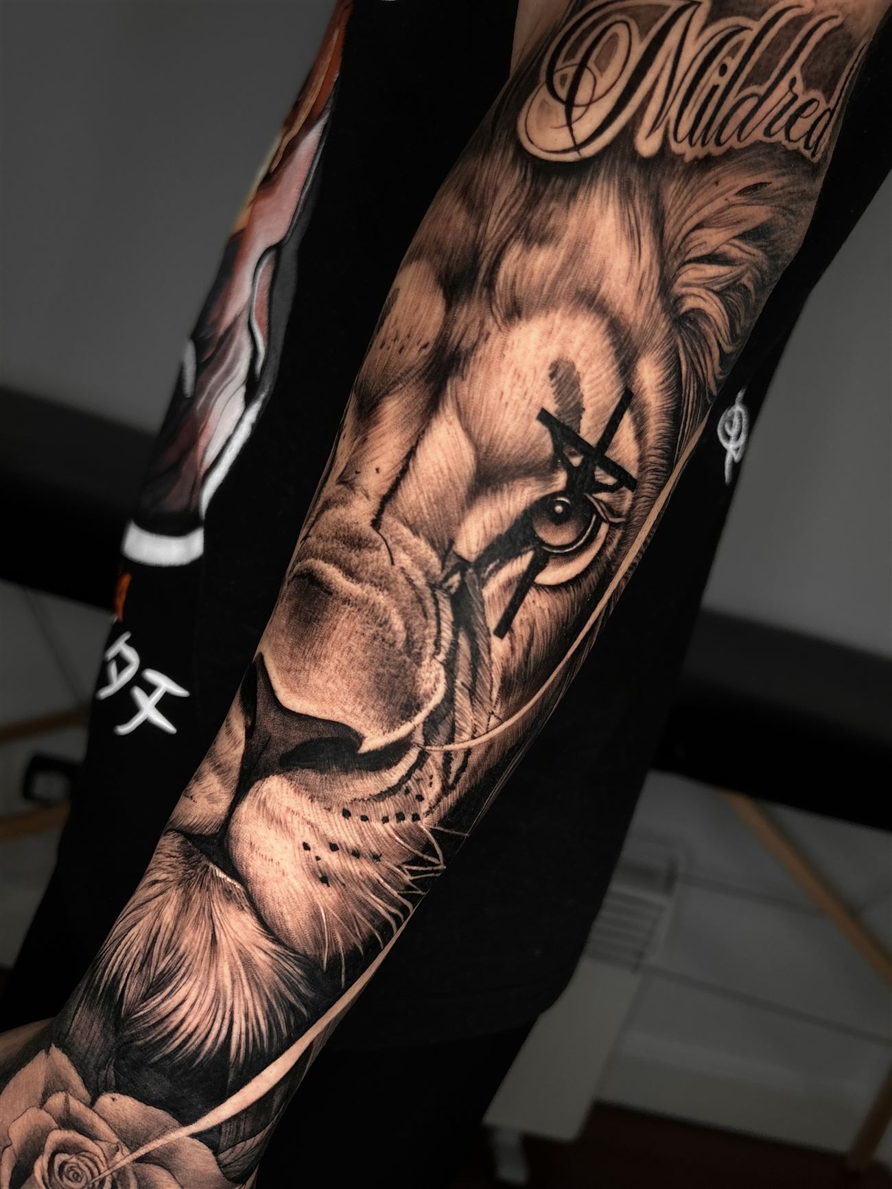 Tatuaje de realismo en blanco y negro de una cabeza de león a lo largo de todo el antebrazo